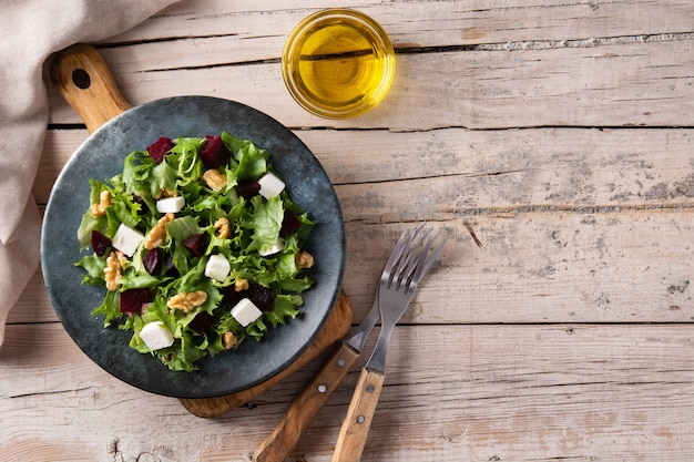 Salada de beterraba com queijo feta, alface e nozes na mesa de madeira