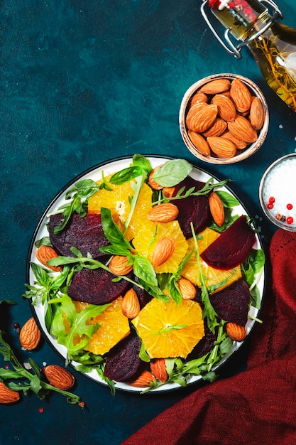 Salada de beterraba fresca com rúcula laranja e amêndoas em fundo azul Comida de verão saudável vegana Configuração plana Espaço de cópia