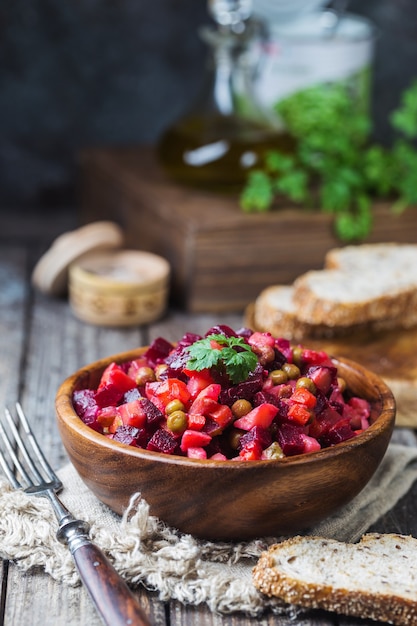 Salada de beterraba russa com vinagrete em tigela de madeira com pão de centeio, fundo rústico