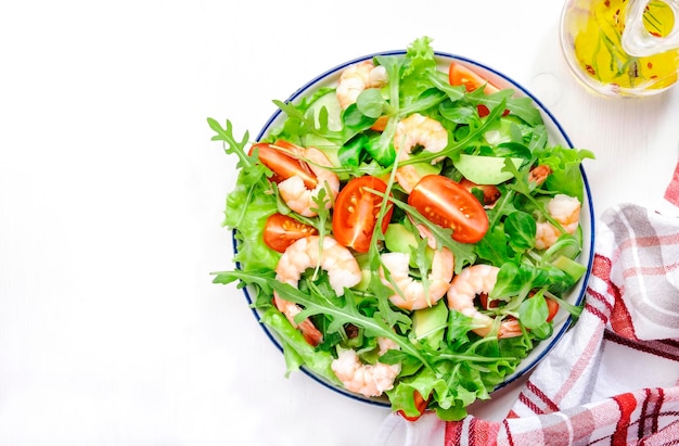 Salada de camarão com tomate cereja rúcula abacate e molho de limão óleo sobre fundo branco Vista superior