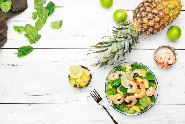Salada de camarão de abacaxi com abacate de espinafre e limão na mesa de cozinha de madeira branca vista superior Alimentação saudável alimentação equilibrada dieta limpa conceito de perda de peso