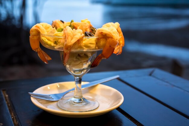 Salada de coquetel com camarão e frutos do mar em uma mesa de madeira contra o fundo do mar