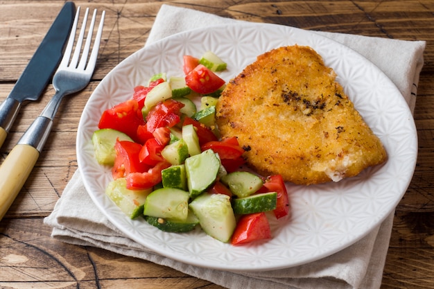 Salada de costeleta e pepino de frango com tomate em uma mesa de madeira