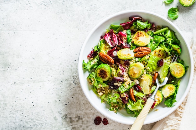 Salada de couve de Bruxelas frita com quinoa, cranberries e nozes em tigela branca