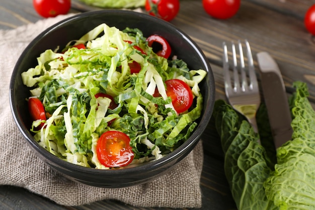 Salada de couve lombarda e tomate servida em tigela na mesa de madeira