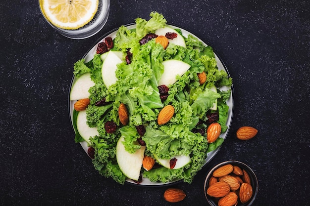 Salada de couve vegana com maçãs secas e amêndoas Comida saudável vista superior mesa de cozinha preta