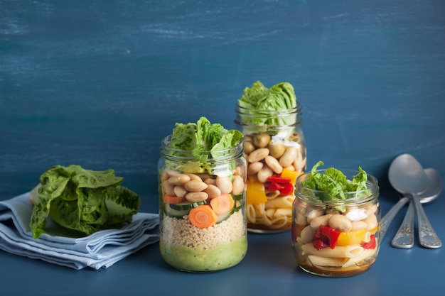 Salada de cuscuz e macarrão vegana em frascos de pedreiro com feijão de legumes