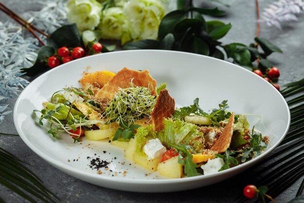 Salada de dieta de verão com folhas de alface, melancia, pêssego e queijo feta. em um espaço de cópia de fundo azul claro.