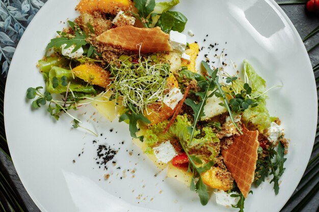 Salada de dieta de verão com folhas de alface, melancia, pêssego e queijo feta. em um espaço de cópia de fundo azul claro.