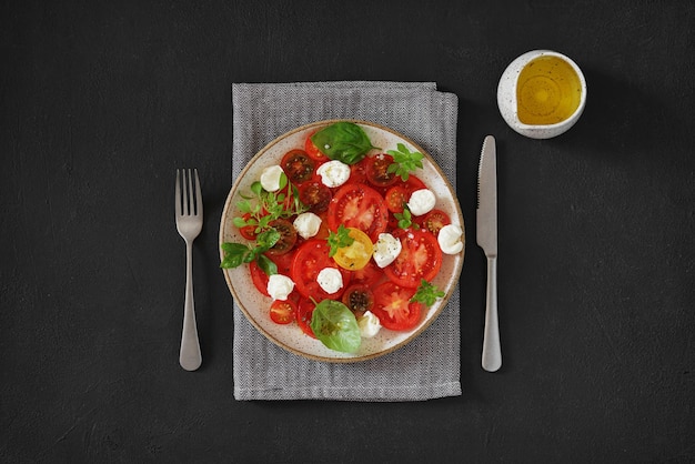 Salada de dieta fresca de verão com manjericão de queijo mussarela de tomate e azeite em fundo escuro