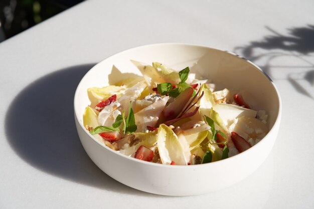 Salada de endívia com queijo de cabra, morango e nozes. Salada de folhas de endívia belga na mesa