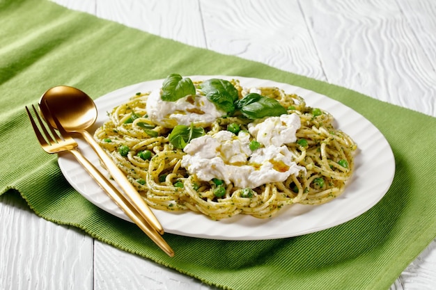 Salada de espaguete de verão com molho pesto ervilhas verdes folhas de manjericão e queijo burrata em um prato cozinha italiana