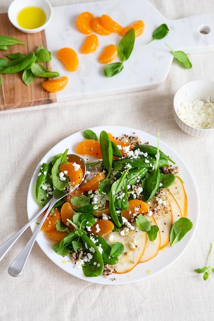 Salada de espinafre e quinua com peras, laranjas e ricota. Preparação de refeições saudáveis. Pratos à base de plantas. Vida Verde. Receita vegana. Estilo de comida. Cozinha Vegetariana. Alimentação saudável. Conceito de comida de perda de peso.