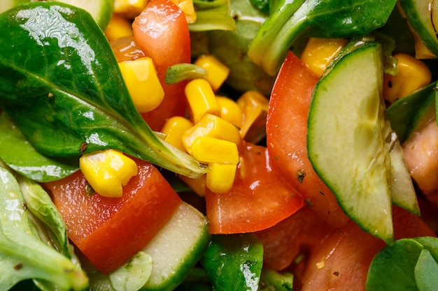 Salada de espinafre, milho, tomate e pepino com azeite. A comida é uma nutrição adequada. Comida vegetariana