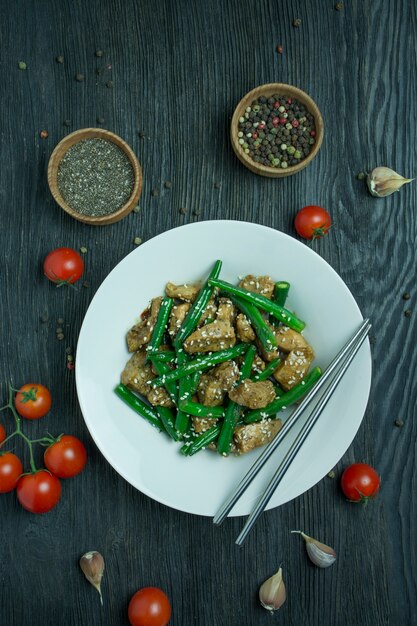 Salada de feijão verde e carne, polvilhada com sementes de gergelim. servindo de salada quente com feijão verde. salada com aspargos. comida asiática. fundo de madeira escuro.