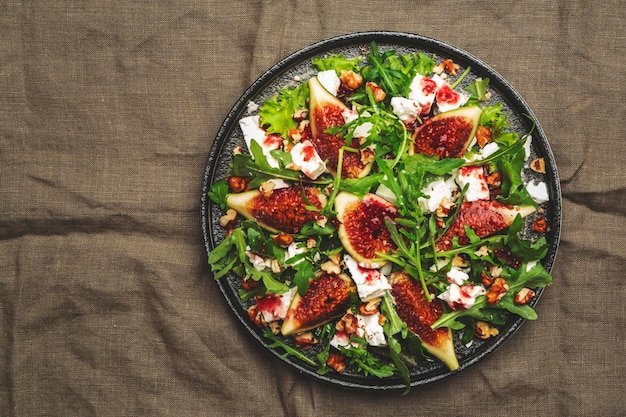 Salada de figo com queijo branco, nozes, rúcula e molho de geleia no espaço de cópia de vista superior de fundo verde ferrugem