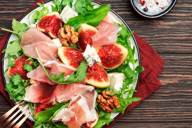 Salada de figo de verão com jamon blue cheese nozes rúcula no antigo espaço de cópia de fundo de mesa de cozinha de madeira