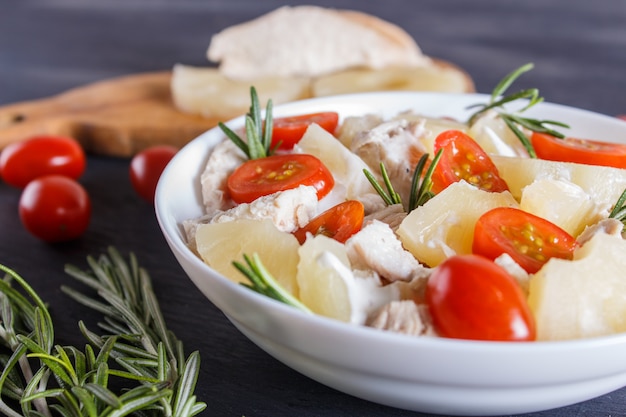 Salada de filé de frango com alecrim, abacaxi e tomate cereja em madeira azul escuro