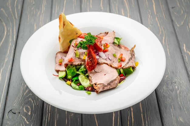 Salada de folhas com rosbife fatiado e tomate cereja seco ao sol