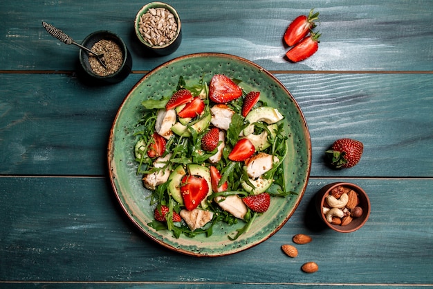 Salada de frango com abacate rúcula e morangos. prato com um alimento dietético cetônico. vista do topo