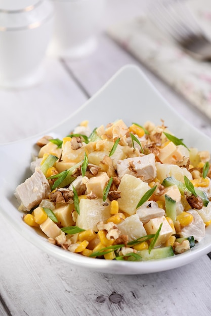 Salada de frango com abacaxi, milho e pepino temperada com iogurte grego, nozes trituradas e queijo.