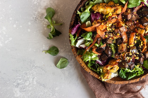 Salada de frango com berinjela, cenoura e salada de mistura verde.