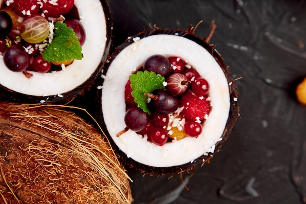 Salada de frutas agrus, groselha, framboesa em tigela de casca de coco