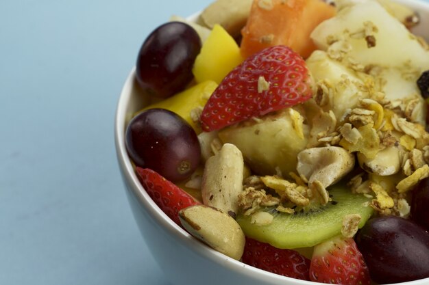 Salada de frutas com castanhas e granola em uma tigela frutas maduras abacaxi manga uva morango mamão