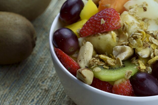 Salada de frutas com castanhas e granola em uma tigela frutas maduras abacaxi manga uva morango mamão