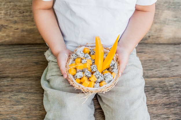 Salada de frutas com fruta do dragão e mamão ao meio coco na mão