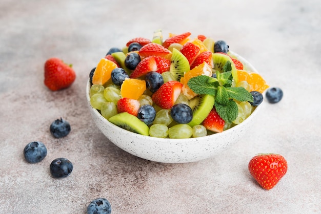 Salada de frutas de mirtilos, morangos, uvas e kiwi em um prato, foco seletivo