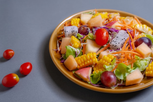 Salada de frutas e vegetais no prato prato em cinza