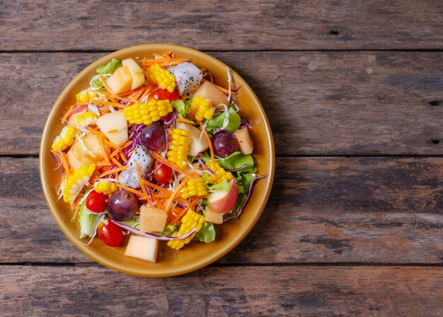 Salada de frutas e vegetais no prato prato na mesa de madeira