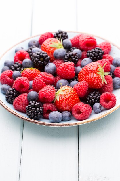 Salada de frutas frescas em um prato sobre uma mesa de madeira. Camada plana, vista superior