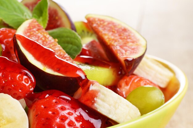 Salada de frutas saudáveis com calda de morango sobre fundo brilhante