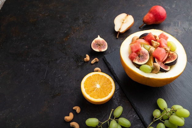 Salada de frutas vegetariana de melancia, uva, figo, pêra, laranja, caju em quadro de ardósia.