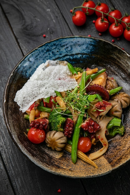 Salada de frutos do mar em um prato escuro e mesa de madeira