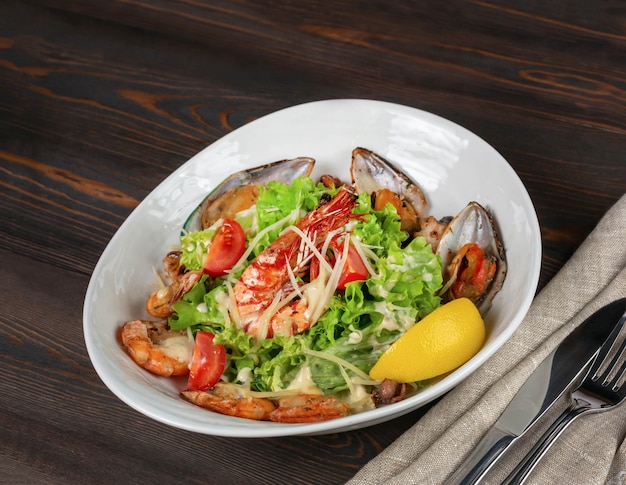 Salada de frutos do mar, tomate e alface polvilhada com parmesão ralado em um fundo de tábuas escuras