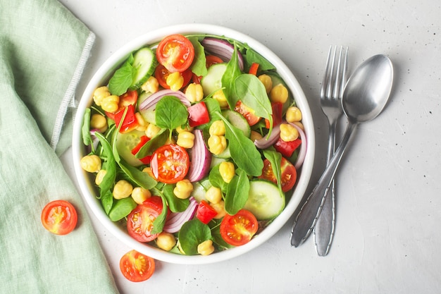 Salada de grão de bico vegetariano preparada com tomate, pepino, cebola roxa, salada de agrião e rúcula. o grão de bico é rico em proteínas e fibras. vista do topo | Foto