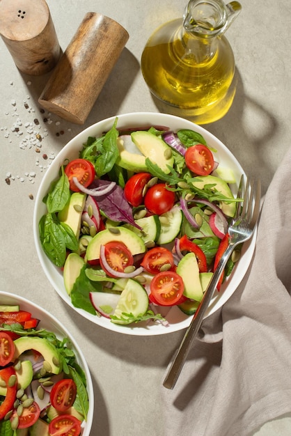 Salada de legumes com abacate de tomate e pepino em um fundo cinza