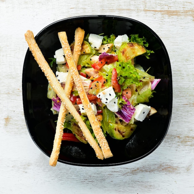 Salada de legumes com abobrinha de frango e queijo feta em um prato preto Vista superior Espaço livre para o seu texto