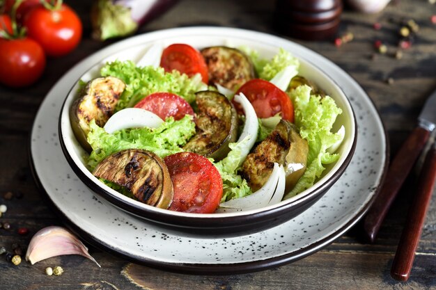 Salada de legumes com alface, tomate e berinjelas grelhadas na mesa da cozinha.