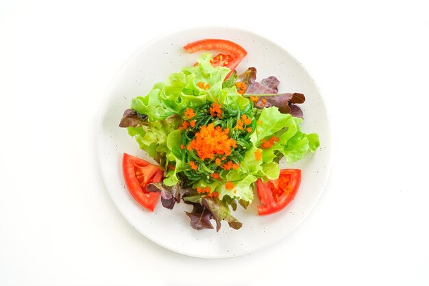 Salada de legumes com algas japonesas e ovos de camarão na mesa branca