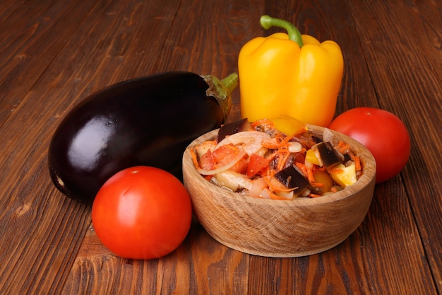 Salada de legumes com berinjela e outros ingredientes em uma mesa de madeira