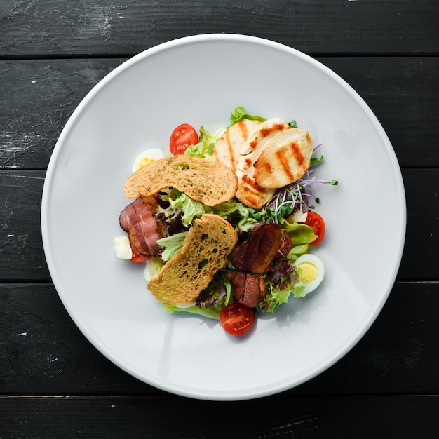 Salada de legumes com filé de frango e bacon. Vista superior, espaço livre para o seu texto. Estilo rústico.