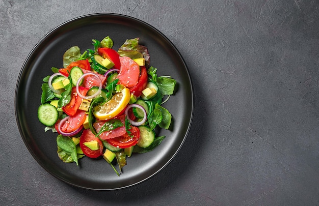 Salada de legumes com salmão e abacate em um fundo escuro