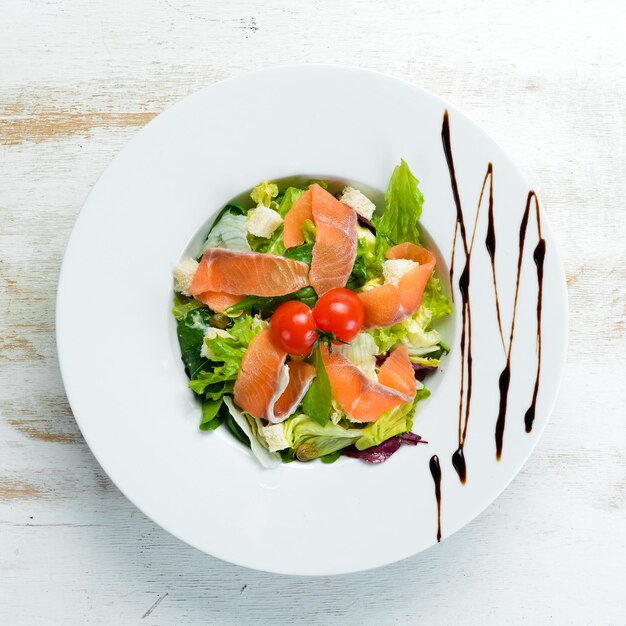 Salada de legumes com salmão salgado e tomate cereja. Salada Caesar com salmão. Vista do topo. Espaço livre para o seu texto.