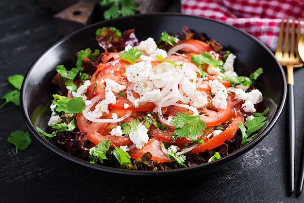 Foto salada de legumes com tomate, alface fresca, queijo de pasta mole e cebola. comida de dieta saudável.