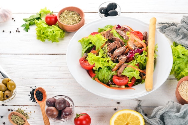 Salada de legumes com vitela e cogumelos Em um fundo branco de madeira Vista superior Copie o espaço para o seu texto