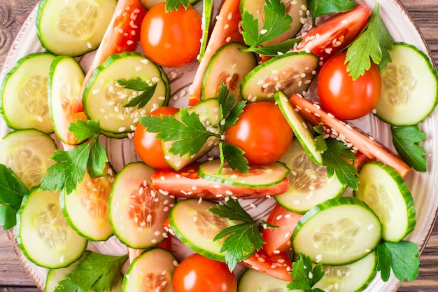Salada de legumes de pepinos frescos, tomates, salsa e gergelim em um prato.